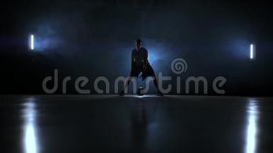 篮球运动员在球场上运球，球在黑暗的房间里，背光在烟雾中缓慢运动